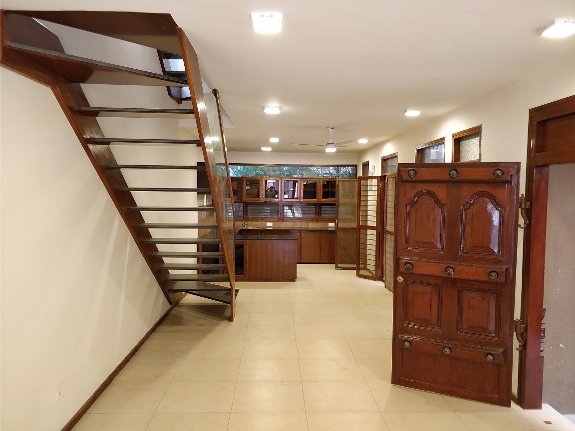 Open plan interior with wooden staircase and kitchen in the background
